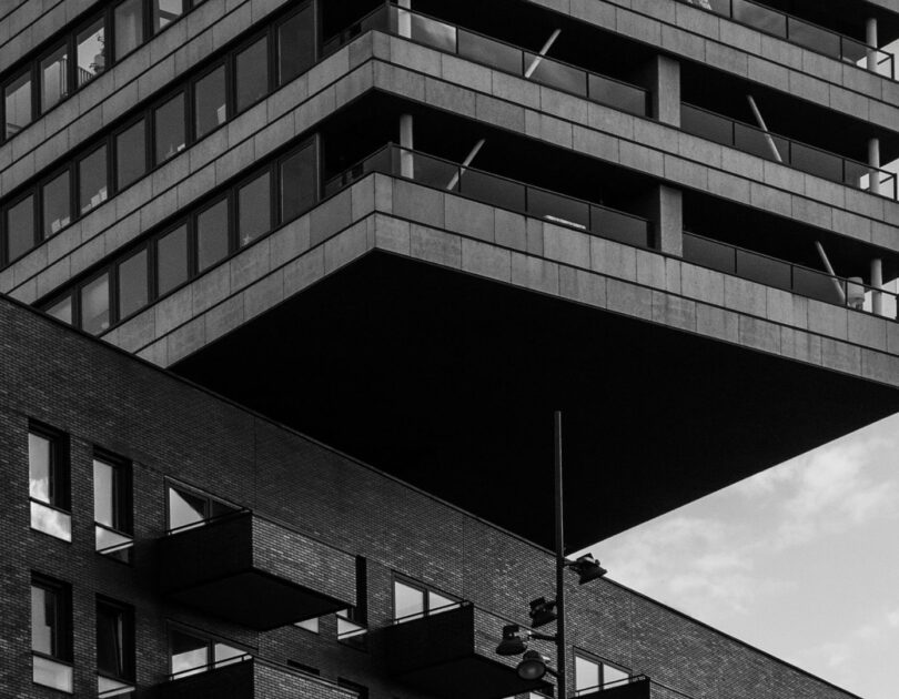 Fachada de edifício moderno em preto e branco com volumes em balanço e detalhes em alvenaria